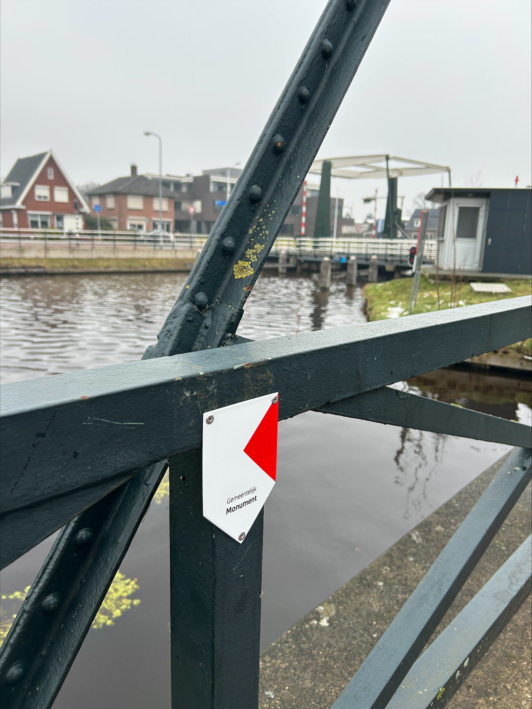 Het monumentenschildje op de historische trambrug in Nieuw-Amsterdam markeert de status van de brug als gemeentelijk monument. De brug zal in het komende jaar worden gerestaureerd om haar cultuurhistorische waarde te behouden voor de toekomst.
