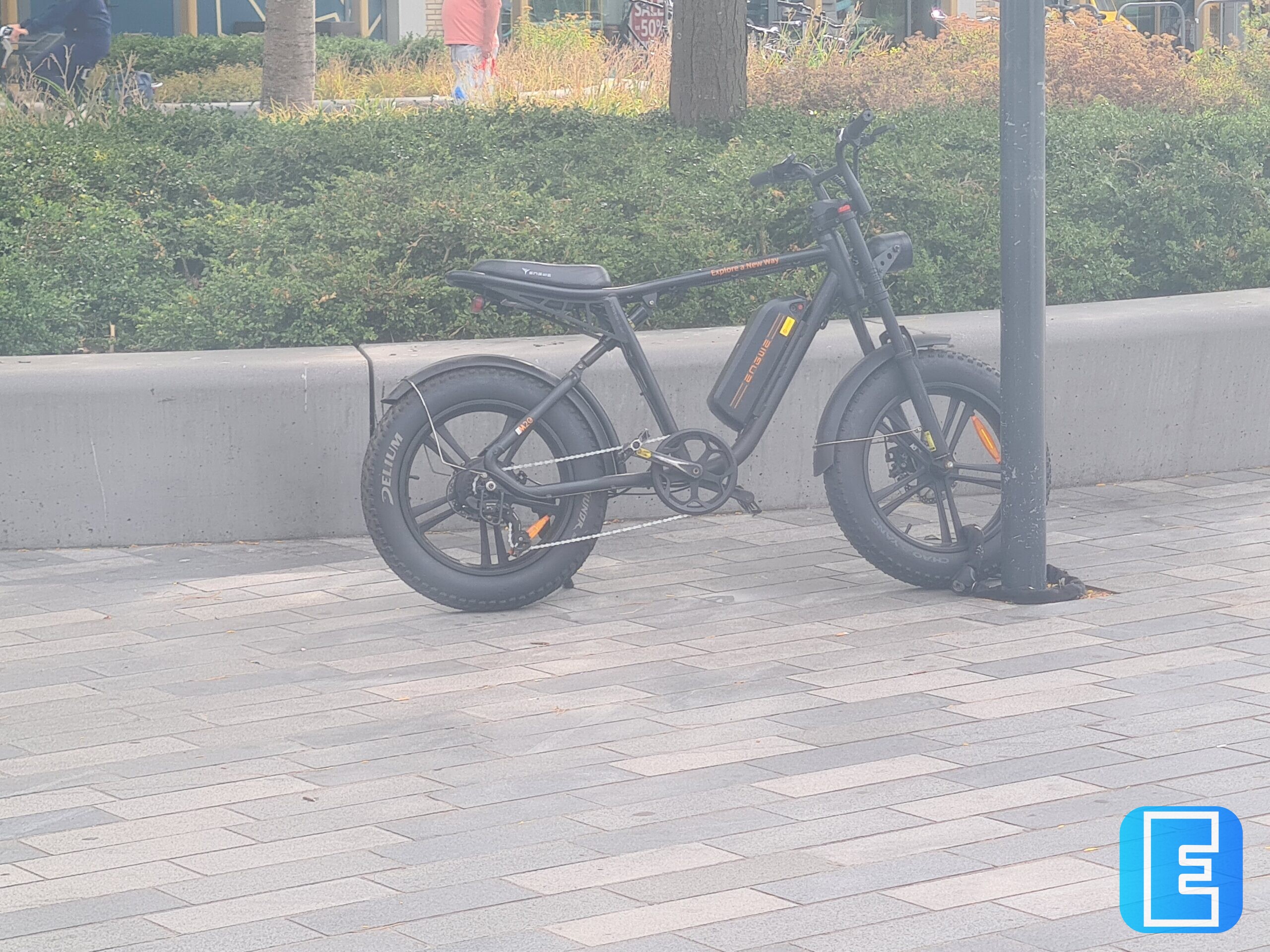 Zwarte elektrische fatbike vastgemaakt aan een paal op de stoep